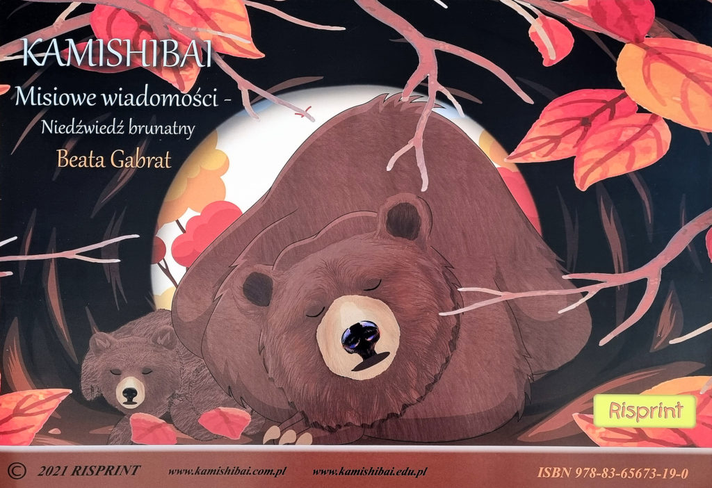 Strona tytułowa teatrzyku kamishibai pt. "Misiowe wiadomości - Niedźwiedź brunatny". W norze - jaskini śpią dwa brunatne niedźwiedzie, duży i mały. Wokół gałęzie i jesienne liście.