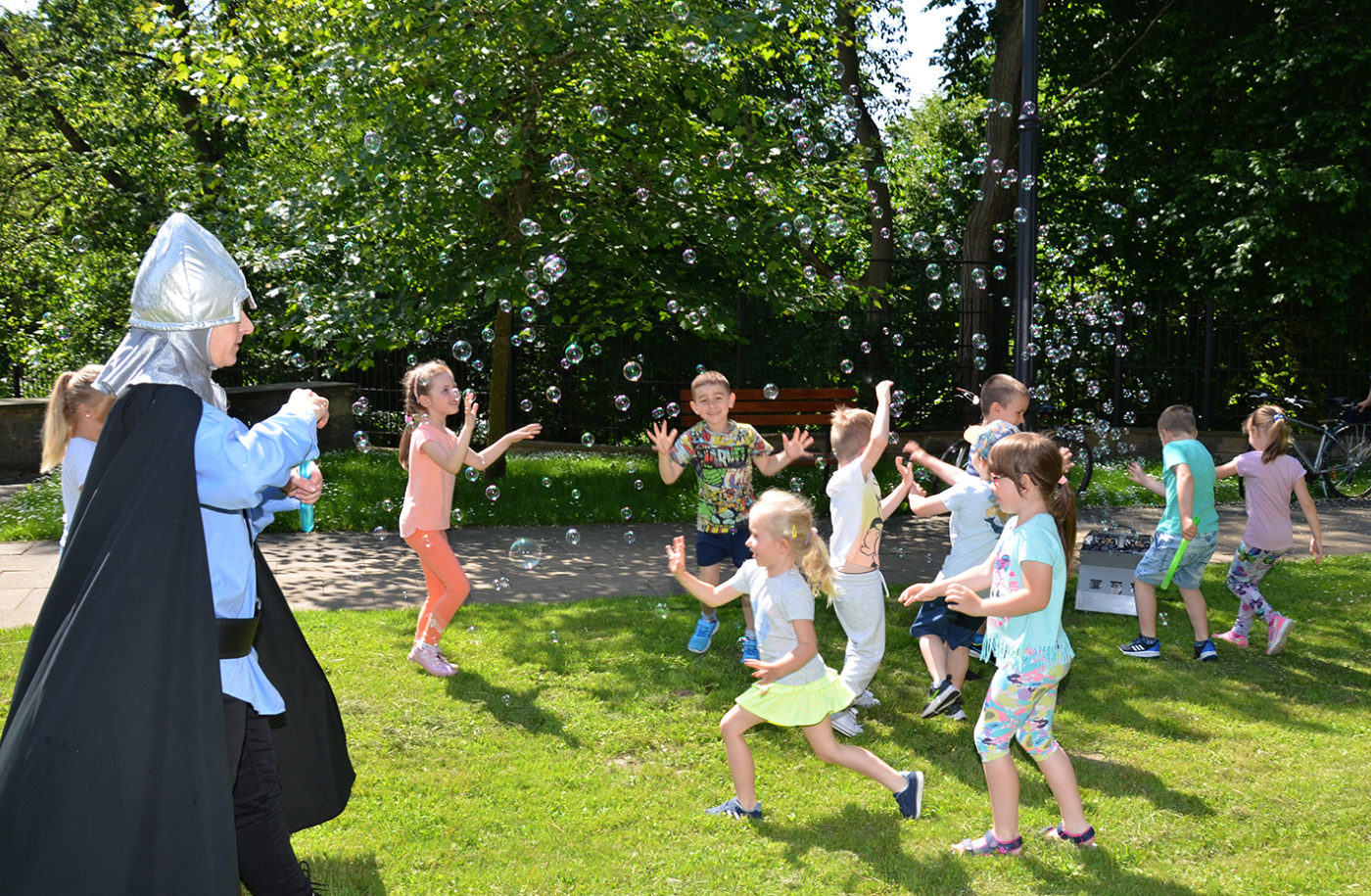 na zdjęciu: dzieci w ruchu łapiące  bańki na świeżym powietrzu.