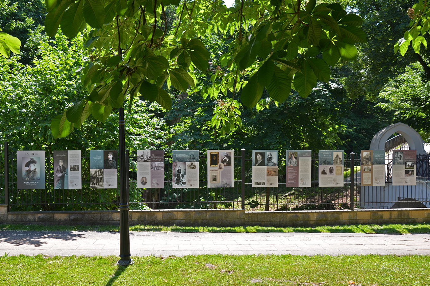 Na zdjęciu: widok na wystawę pt. "Konopnicka. Kobieta niepokorna" zamontowaną na ogrodzeniu  wokół terenu Biblioteki Miejskiej. 