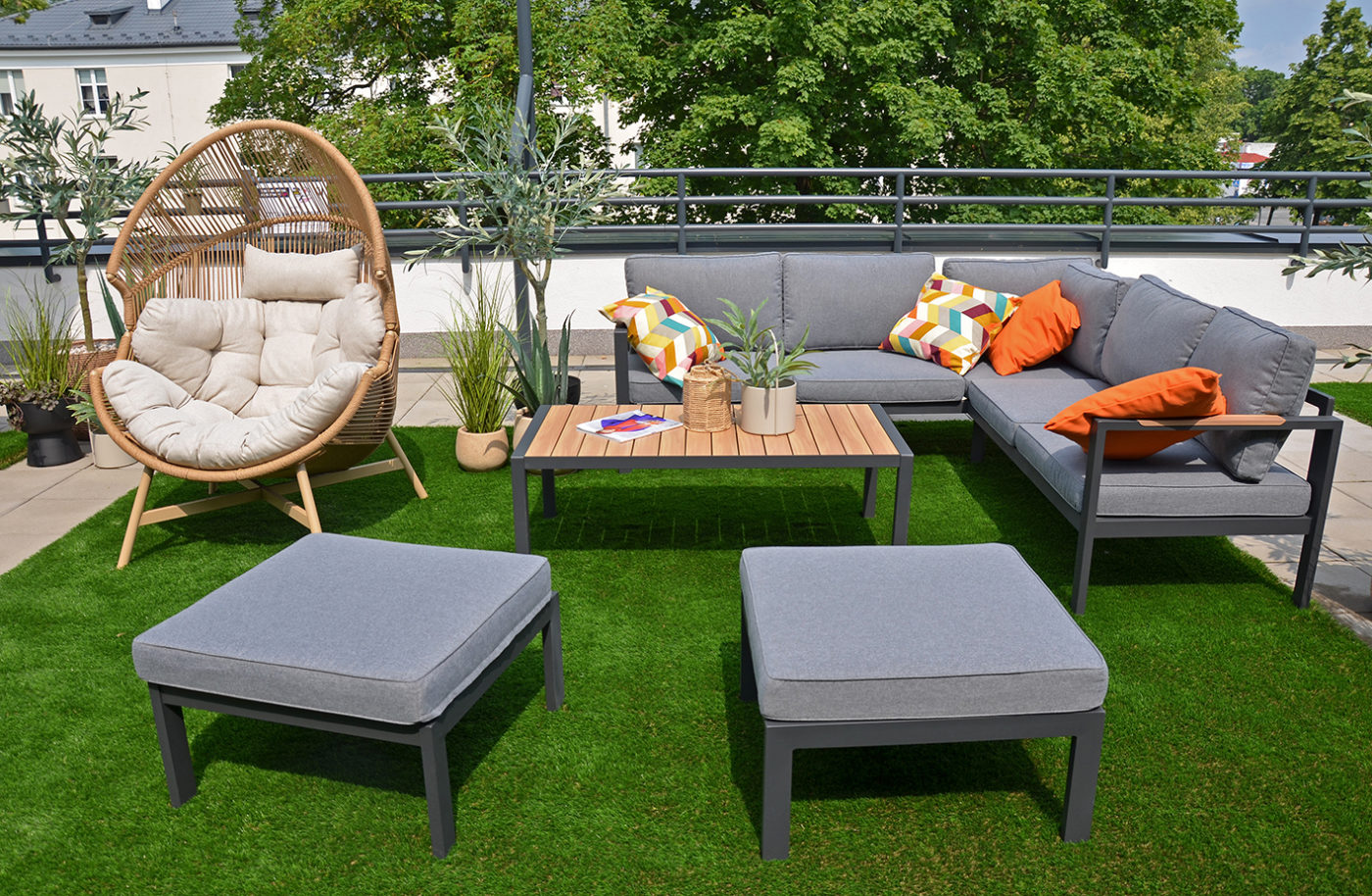 Taras Mediateki. Na zdjęciu narożnik z poduchami, stolik i fotel. Wokół donice z kwiatami.